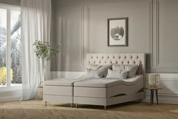 Elegant sänggavel i ullat tyg och boxmadras i naturnyanser, perfekt för en lyxig sovrumsmiljö.